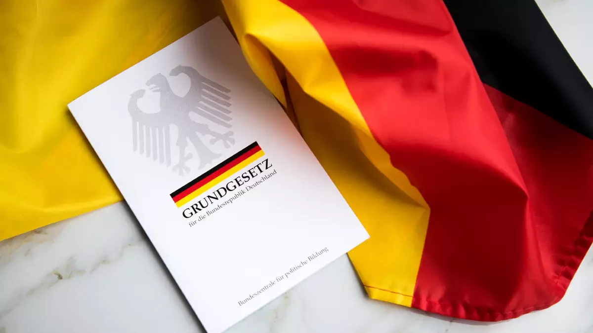 Grundgesetz-Buch der Bundesrepublik Deutschland auf Schwarz-Rot-Gold-Flagge. Foto: Adobe Stock | Christin Klose